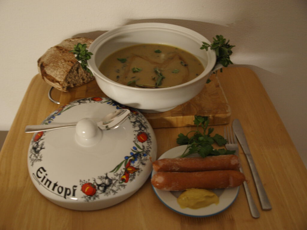 Fertige Kartoffelsuppe mit Majoran in Terrine und Bockwürste mit Senf auf Teller